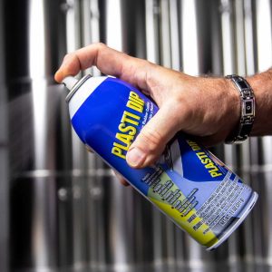 Hand spraying a can of 11oz Plasti Dip at an angle against a silver background
